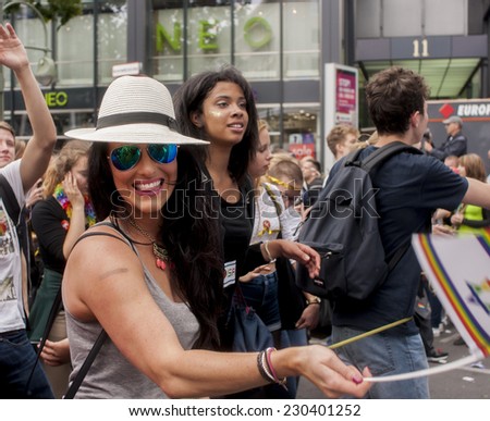 BERLIN, GERMANY - JUNE 21, 2014: Christopher Street Day. Crowd of people Participate in the parade celebrates gays, lesbians, and transgenders. Prominent in the image, elaborately dressed woman