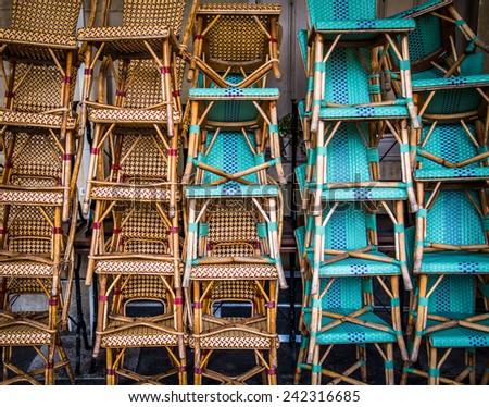 Wicker bistro chairs stacked outside a bistro/cafe in Paris France.