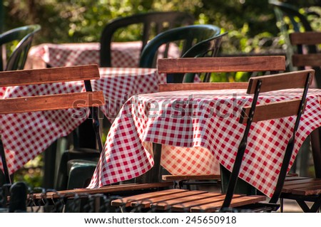 Gingham table cloths cover tables at an outdoor cafe in a garden in Paris France.