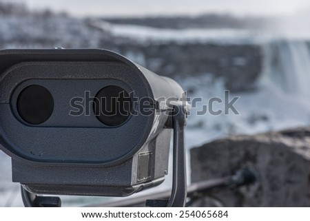 A set of tourist binoculars point to the distant out of focus Niagara Falls.