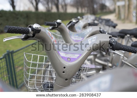 Looking over the handle bars of a row of rental bicycles in Paris France.