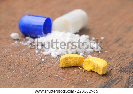 close up broken medicine tablet and opened medicine capsule pill with powder background