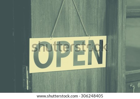 Open sign broad hanging on wooden door in street cafe.Retro color style.