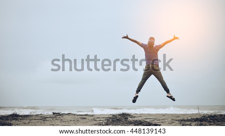 Feel good and freedom concept. Copy space of happy man jumping on beach. Vintage tone color style.