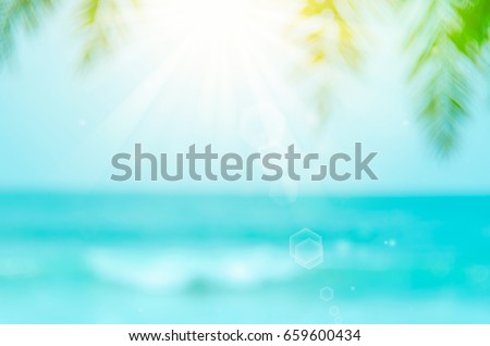 Blur palm leaf on beach with bokeh wave sun light abstract background.
