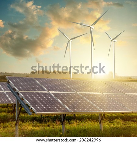 Wind generators turbines and solar panels on sunset summer landscape