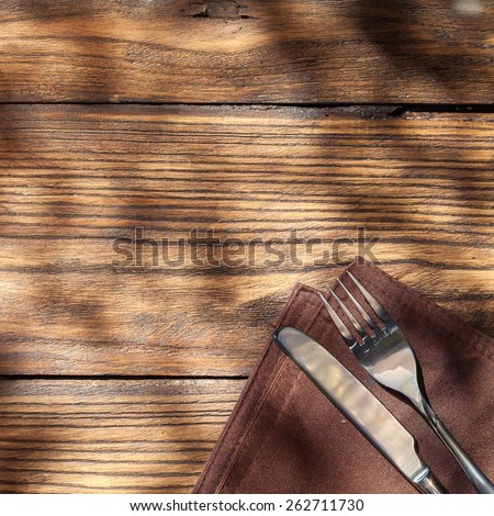 Empty board with fork and knife on wooden table. Top view