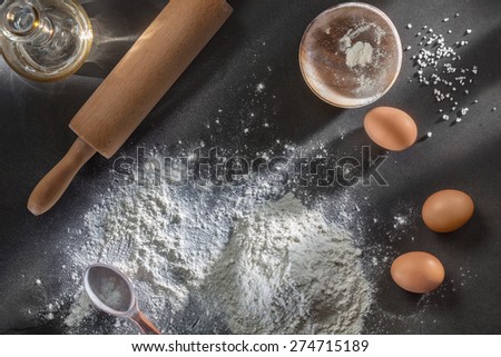 flour and ingredients on black table. Top view