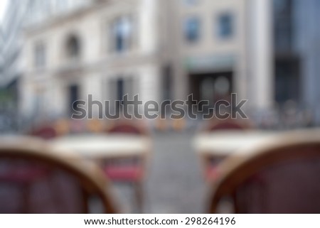 Background of blurred cafe on street of european city. Tables and chairs outside in natural bokeh