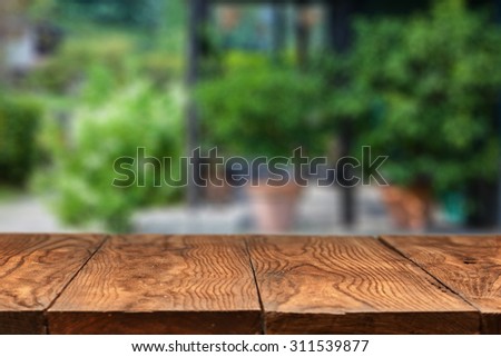 Empty wooden table against summer backyard or patio with green plants on background