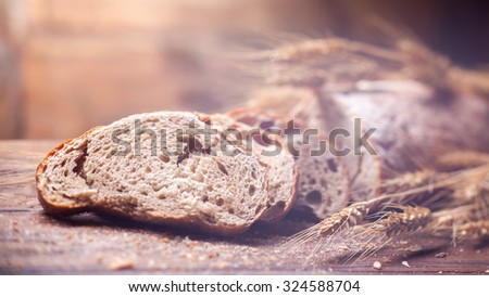 Bread and wheat on wooden table, shallow DOF, raw image. Header for website