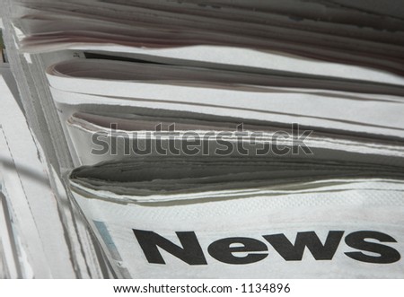 Stack of newspapers with focus on the word 'news' on top paper.