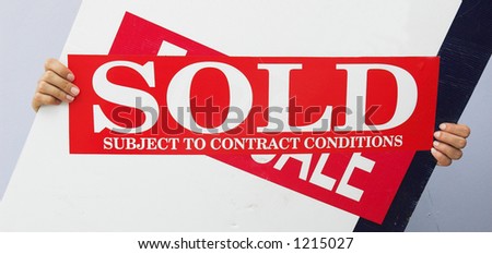 A real estate sign with sold strip added held up by hands.
