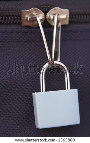 Padlock securing suitcase zips. Shallow focus on lock through zips.