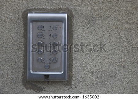 Security numeric keypad with letters mounted in solid concrete wall.