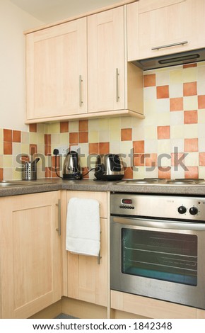 Contemporary apartment kitchen with tiled splashback and stainless steel stove.