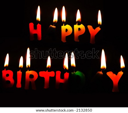 Happy Birthday candles alight against a dark background