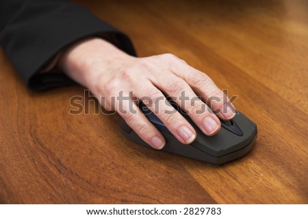 Woman\'s hand using a wireless computer mouse. Focus is on the front of the mouse / end of the fingers.