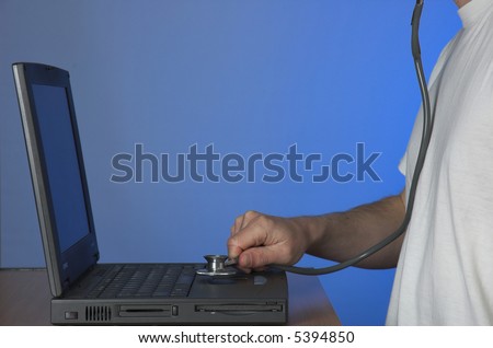 Man working on faulty laptop computer with a doctor\'s stethoscope. Computer maintenance concept.