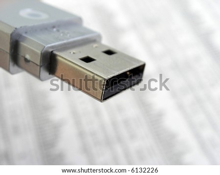 Macro shot of usb memory stick over blurred background financial data in a newspaper.