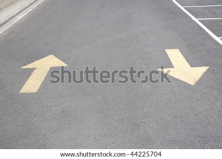 Directional arrows in parking lot.  Horizontally framed shot.