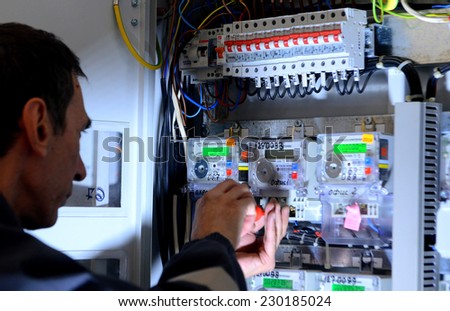 Electrician builder engineer inspecting electric counter equipment in distribution fuse box in building on Sofia, Bulgaria May 13, 2014