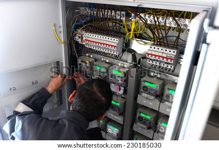 Electrician builder engineer inspecting electric counter equipment in distribution fuse box in building on Sofia, Bulgaria May 13, 2014