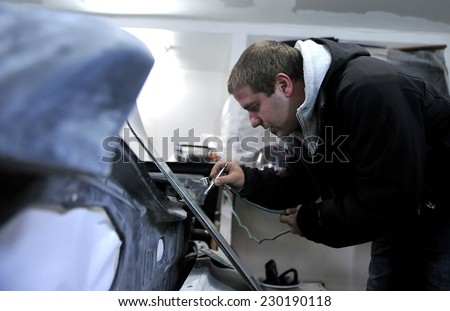 Man painting the body of a car with special suit in Sofia, Bulgaria Jan 4, 2012