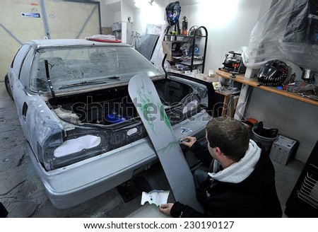 Man painting the body of a car with special suit in Sofia, Bulgaria Jan 4, 2012
