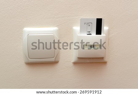 Electronic lock with card inserted and light switches on wooden wall in hotel room