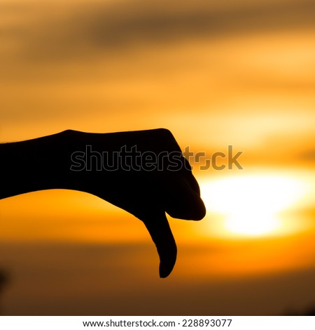 Hand silhouette under a sunset background,The symbol of a hand with meaning unlike.