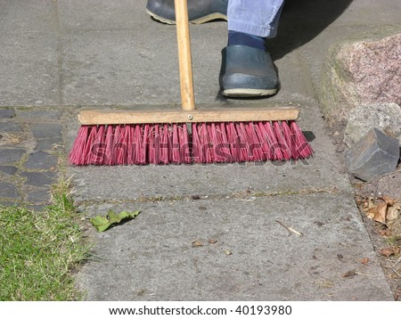 Cutout man with street brush sweeping flag stones