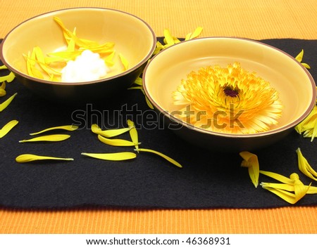 Beauty products of marigold on black and orange background