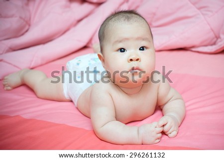 Asian baby girl wear daiper and be inattentive on pink bed