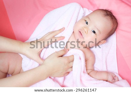 Mom rub her baby to dry whit pink towel