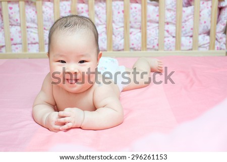 Asian baby girl scowl on pink bed