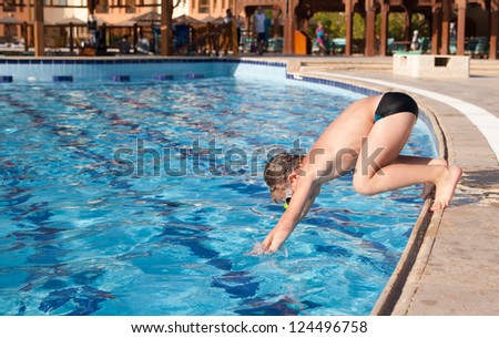 Boy in glasses jumping into the pool