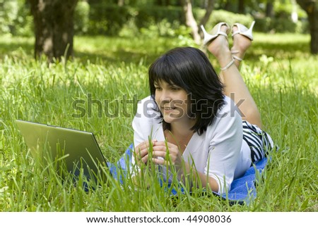 Young woman with notebook lying in the park