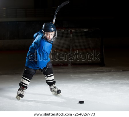 Young hockey player ready to make a strong shot against dark background