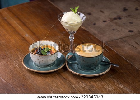 Creme brulee dessert, cup of cappuccino coffee and ice cream on wooden table