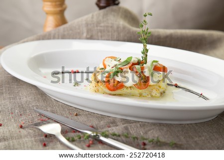 Cooked fish fillet with tomatoes and white sauce on the table