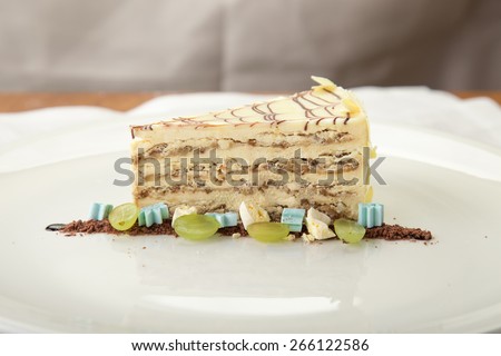 Slice of vanilla cream cake decorated with grape on the table