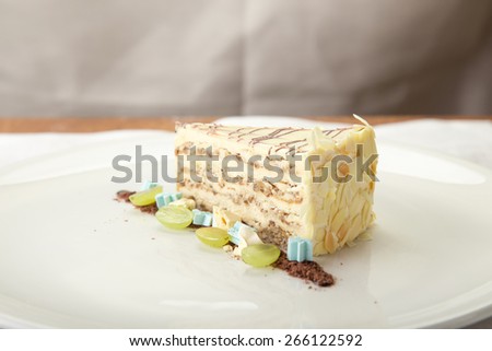 Slice of vanilla cream cake decorated with grape on the table