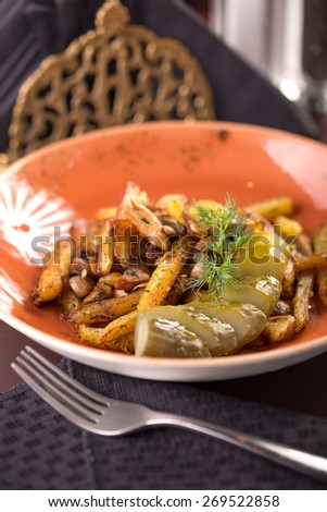 Fried potatoes with pickles and dill on the table at restaurant