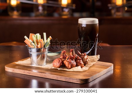 Chicken wings with blue cheese dip and glass of beer isolated on wooden table
