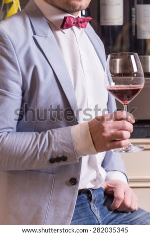 Man in suit and bow tie holding glass of red wine