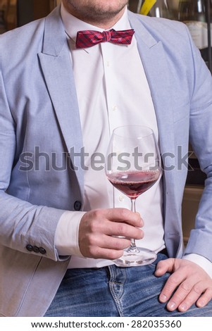 Man in suit and bow tie holding glass of red wine