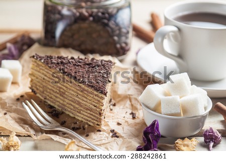 Chocolate cake with dessert fork and cup of coffee on wooden background