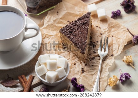 Chocolate cake with dessert fork and cup of coffee on wooden background