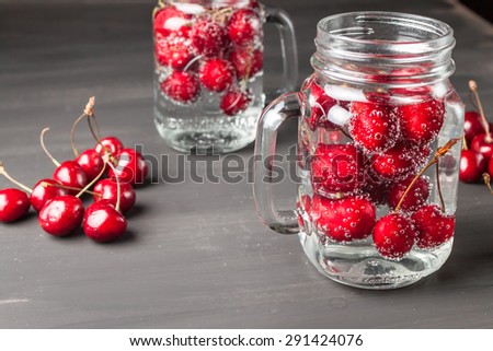 Two glasses of sweet cherry lemonade on black background